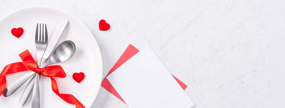 Valentine's Day, Mother's Day, holiday dating meal, banquet design concept - White plate and red ribbon on marble background, top view, flat lay.