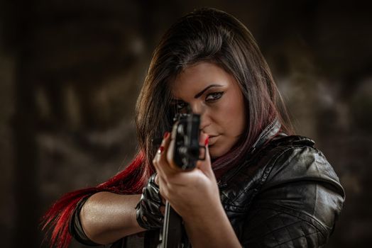 Attractive girl standing in the attitude of aiming and looking through the sight automatic rifle and shooting.