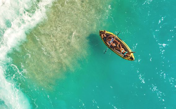 A happy family having fun in a inflatable rubber boat near the sea beach. Beautiful natural background at the summer time from air.