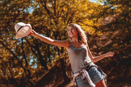 Portrait of a beautiful happy smiling young woman in the nature in early autumn sunny day. Looking away.