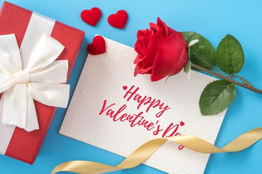 Valentine's Day gift card with greeting word design concept, woman sending gift on vibrant blue background, top view, overhead.