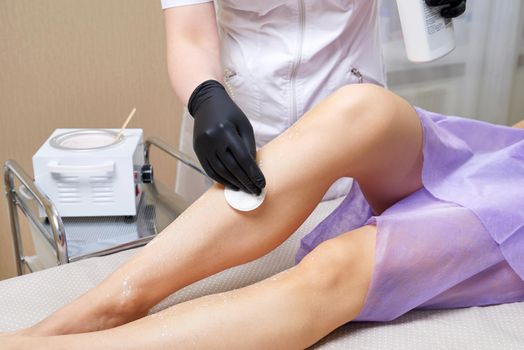 Beautician getting ready to wax female legs in spa center