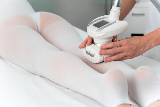 Woman in special white suit getting anti cellulite massage in a spa salon. LPG, and body contouring treatment in clinic