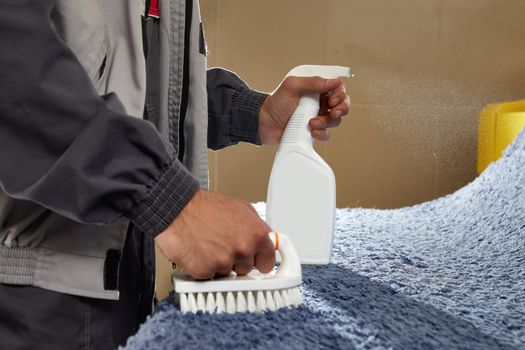 Man using chemical spray to remove stain from carpet in carpet cleaning service
