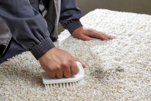 Man Spraying Detergent On Grey Carpet To Remove Stain in professional cleaning service High quality photo