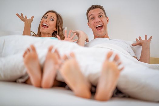 Beautiful young smiling couple having fun in bed in the morning. 