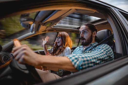 Couple in a car at sunset, with man driving fast and girl scared, screaming and crying.
