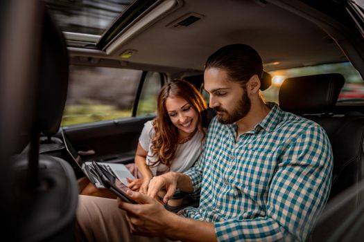 Young confidence business partners working on a business trip on the back seat in car.