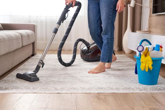 Woman cleaning the carpet with vacuum cleaner in the modern living room