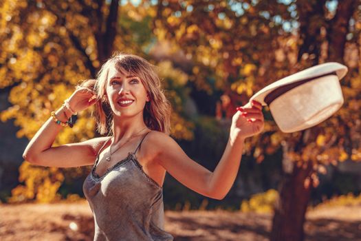 Portrait of a beautiful smiling young woman in the nature in early autumn sunny day. Looking away.