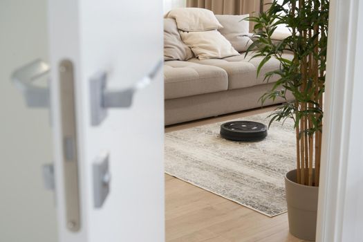 Robotic vacuum cleaner on carpet in cozy living room