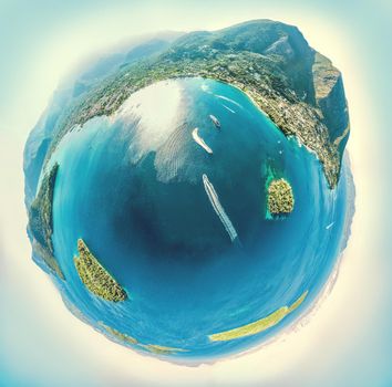 Spherical panorama of a little planet with mountains, little islands, sea coast, villages, rocks, beautiful turquoise and blue sea, and speed boats. View on the Nydri bay on  the eastern coast of the island of Lefkada, Greece.