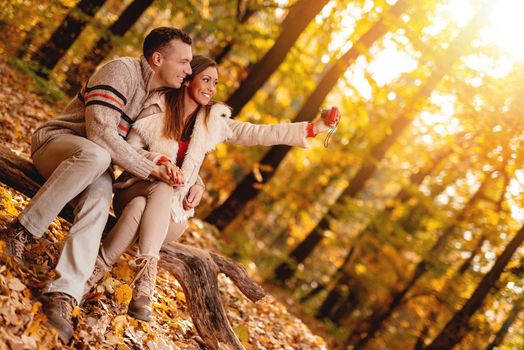 Beautiful smiling couple enjoying and taking selfie in forest in autumn.