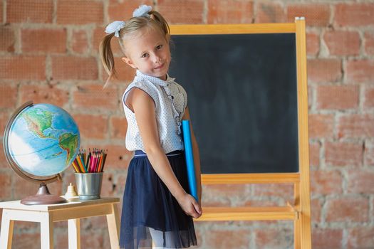 Portrait of caucasian school kindergarten girl with book in her hands, back to school concept