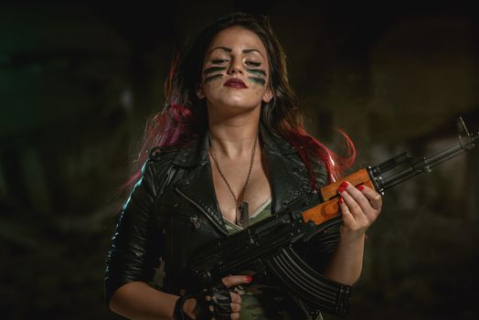 Young attractive military woman with face paint in war paint holding rifle and looking at camera.