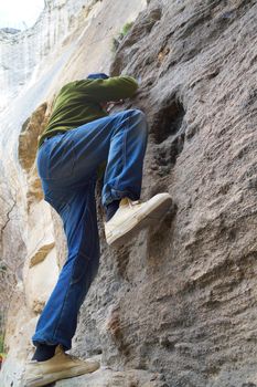 a man in jeans climbing a cliff close-up