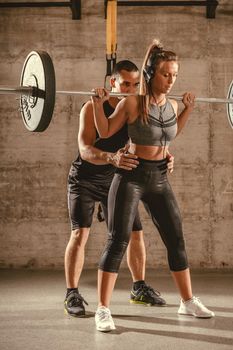 Young woman doing squat exercise at the gym with a personal trainer.