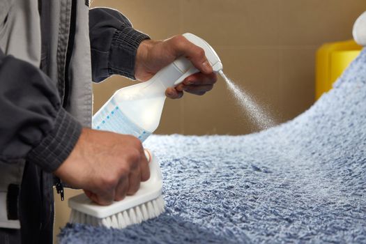 Man using chemical spray to remove stain from carpet in carpet cleaning service