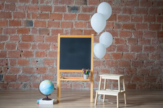 Back to school concept: chalk board, stack of books, globe and teddy bear on brick wall background