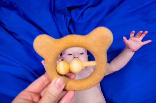 a baby in a tiger diaper on a blue background with a wooden rattle