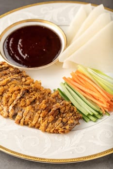 Sliced Peking duck with Hoysin sauce with fresh cucumber, green onion, carrot. served with wheat Chinese pancakes