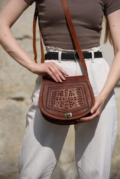 small brown women's leather bag with a carved pattern. street photo