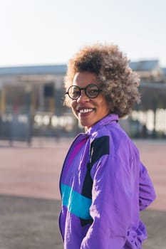 portrait of a smiling african american woman in sportswear looking at camera, concept of active lifestyle and urban sport