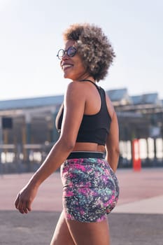 vertical photo of an african american woman in sportswear smiling happy ready to run outdoors, concept of active lifestyle and urban sport