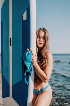 Close up shot of beautiful young caucasian woman with black hair and freckles looking at camera and smiling. Cute woman portrait in a pink bikini posing on a volcanic rock high above the sea