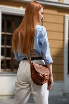 small brown women's leather bag with a carved pattern. street photo