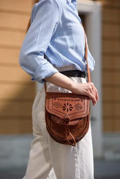 small brown women's leather bag with a carved pattern. street photo