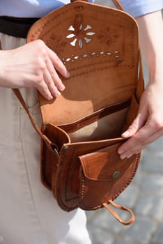 small brown women's leather bag with a carved pattern. street photo