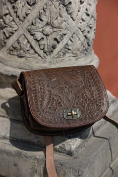 small brown women's leather bag with a carved pattern. street photo