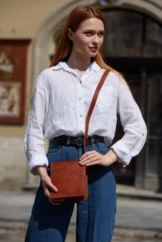 photo of a woman with a small yellow leather bag. the girl is dressed in jeans and white blouse