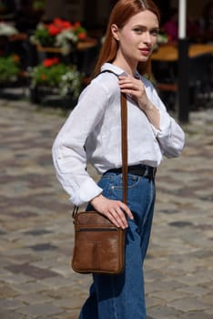 photo of a woman with a small yellow leather bag. the girl is dressed in jeans and white blouse