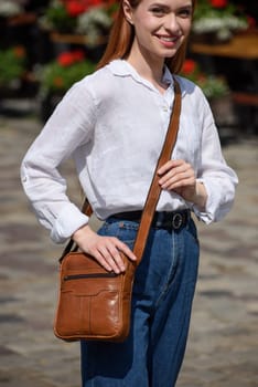 photo of a woman with a small yellow leather bag. the girl is dressed in jeans and white blouse