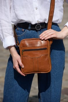 photo of a woman with a small yellow leather bag. the girl is dressed in jeans and white blouse