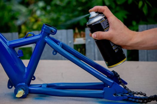 the father paints the child's bicycle with blue paint. selective focus