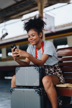 Asian teenage girl african american traveling using smartphone moblie while waiting for a train at a station