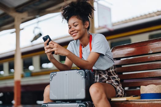 Asian teenage girl african american traveling using smartphone moblie while waiting for a train at a station