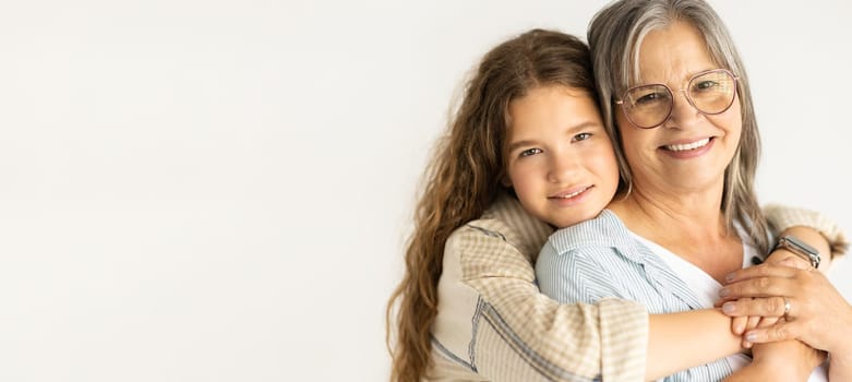 Happy european teen girl hugging old grandmother, enjoy support, isolated on white background, studio, panorama. Love, family relationships, female generation and genetic, beauty care