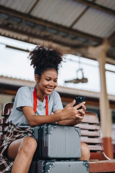 Asian teenage girl african american traveling using smartphone moblie while waiting for a train at a station