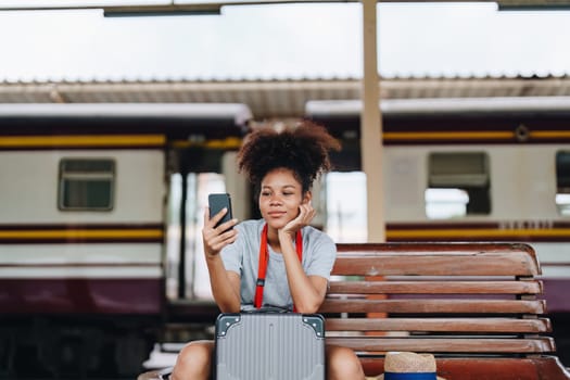 Asian teenage girl african american traveling using smartphone moblie while waiting for a train at a station