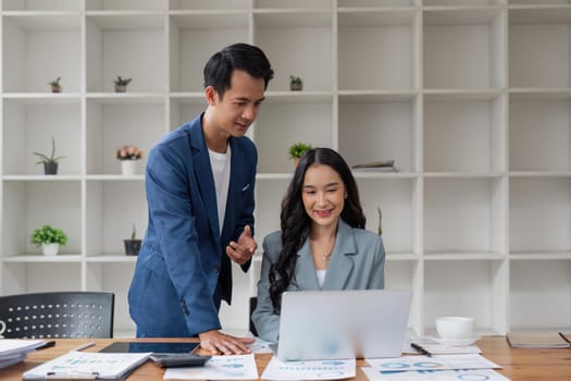 Business man having a discussion with his colleague in an office. Two business people using a laptop in a meeting. Teamwork and collaboration between business professionals.