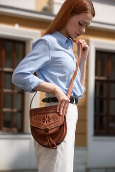 small brown women's leather bag with a carved pattern. street photo