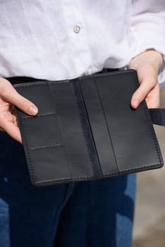 Close-up of a girl's hands with an open purse in her hands. An empty wallet is a woman with no money. Wallet made of black leather.