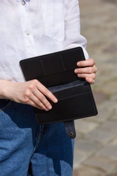 Close-up of a girl's hands with an open purse in her hands. An empty wallet is a woman with no money. Wallet made of black leather.