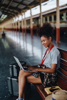 Asian teenage girl african american traveling using computer laptop while waiting for a train at a station