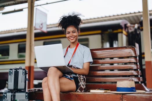 Asian teenage girl african american traveling using computer laptop while waiting for a train at a station