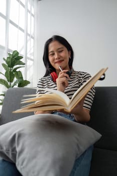 woman sit at sofa hold pencil take notes to paper notebook working studying. Female student businesswoman employee write records to daily planner by hand at home work desk.